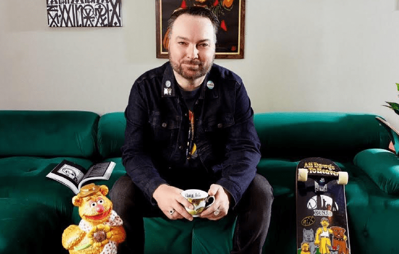 Rick Savage sitting on a green couch. (Photo courtesy Rick Griffin/MarketInk)