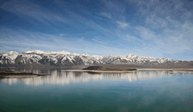 mountain range covered in snow with island and lake