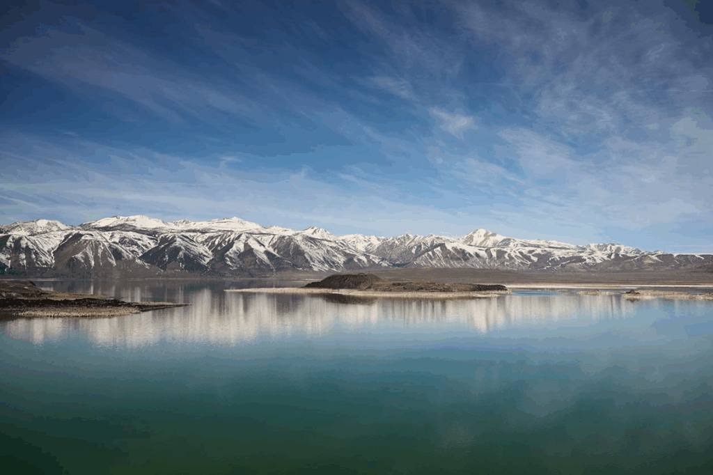 mountain range covered in snow with island and lake