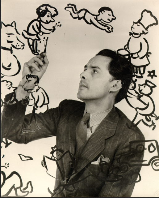 A man in a suit draws cartoon characters on a clear surface, surrounded by his illustrations.