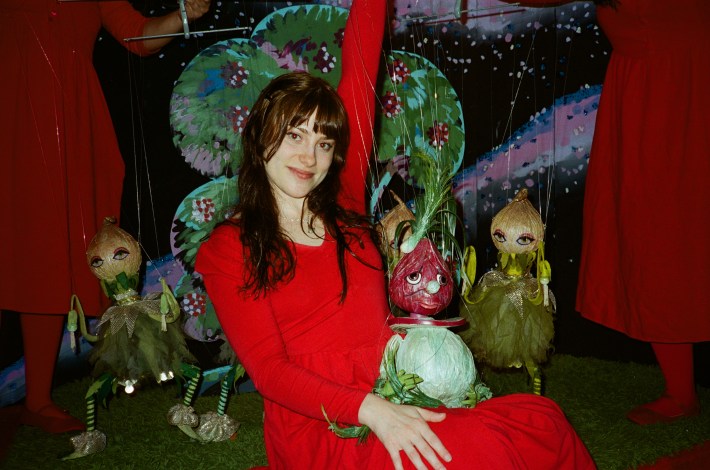a woman in a red outfit holding a puppet of an onion