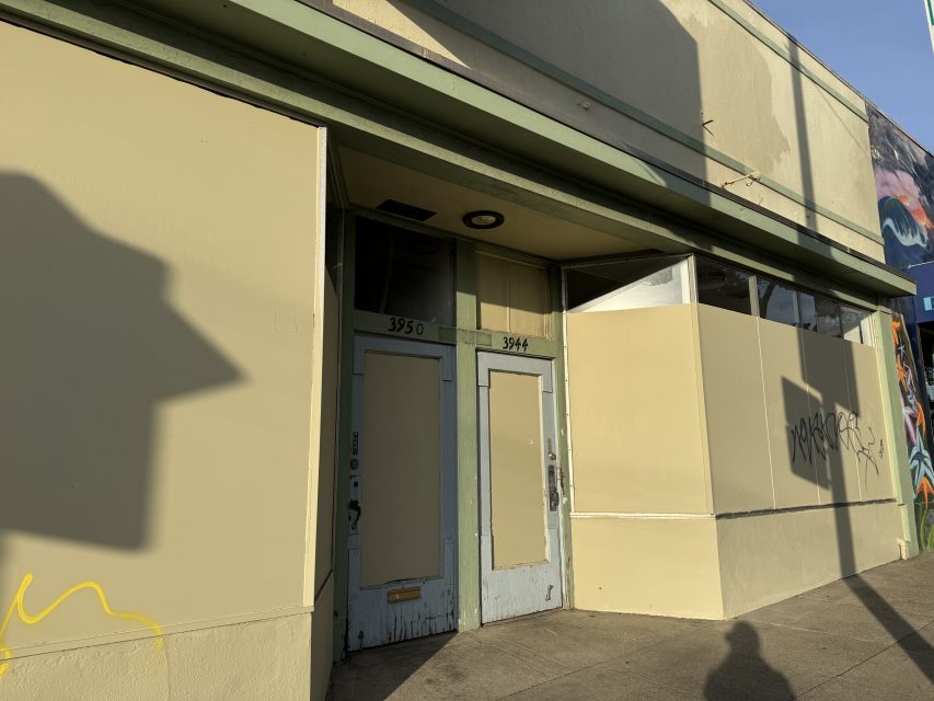 Two closed, weathered doors marked 3950 and 3944 in a beige storefront with graffiti and sunlight casting shadows on the sidewalk.