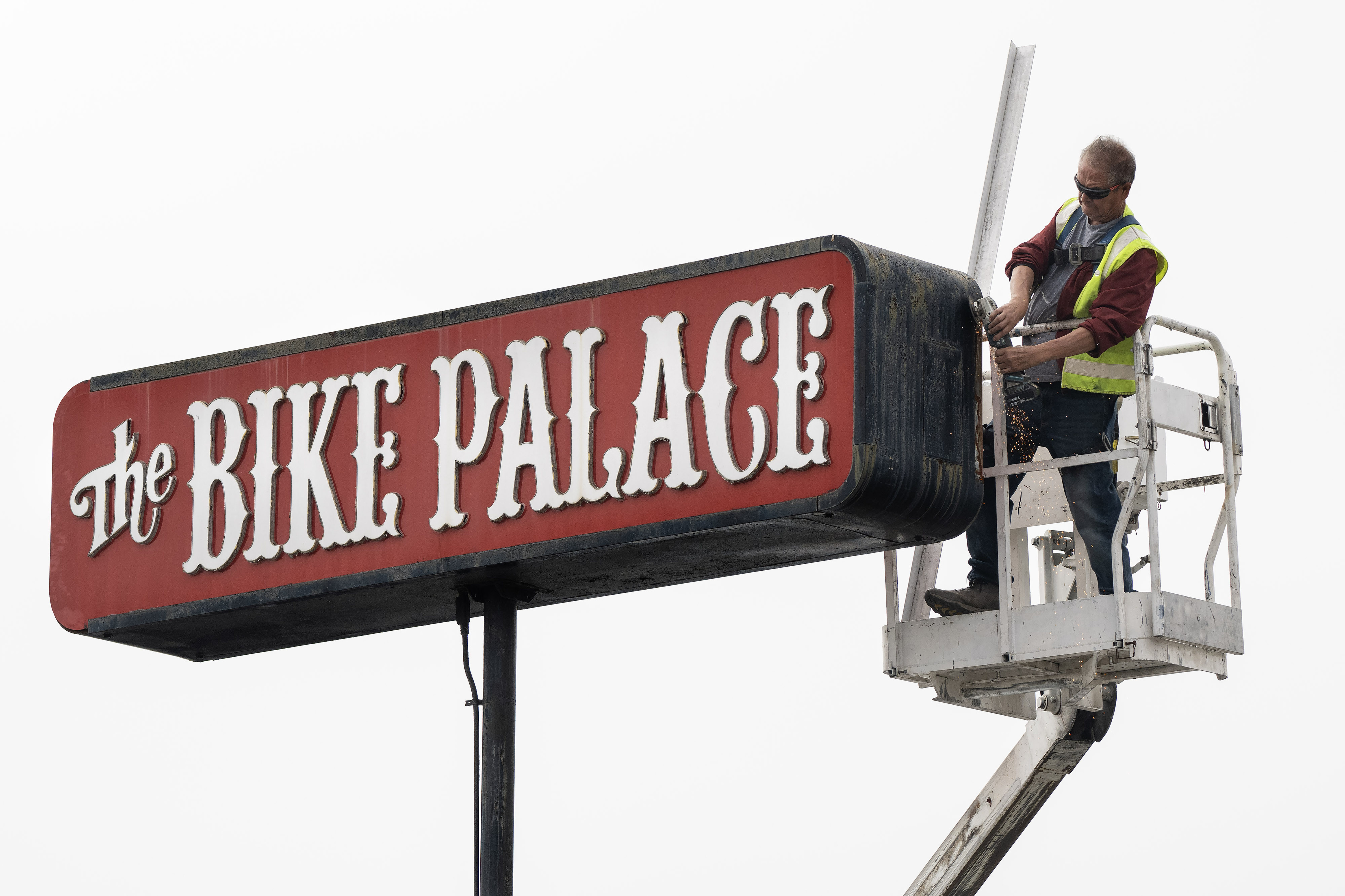 Tony Paze works to remove the iconic Bike Palace sign...
