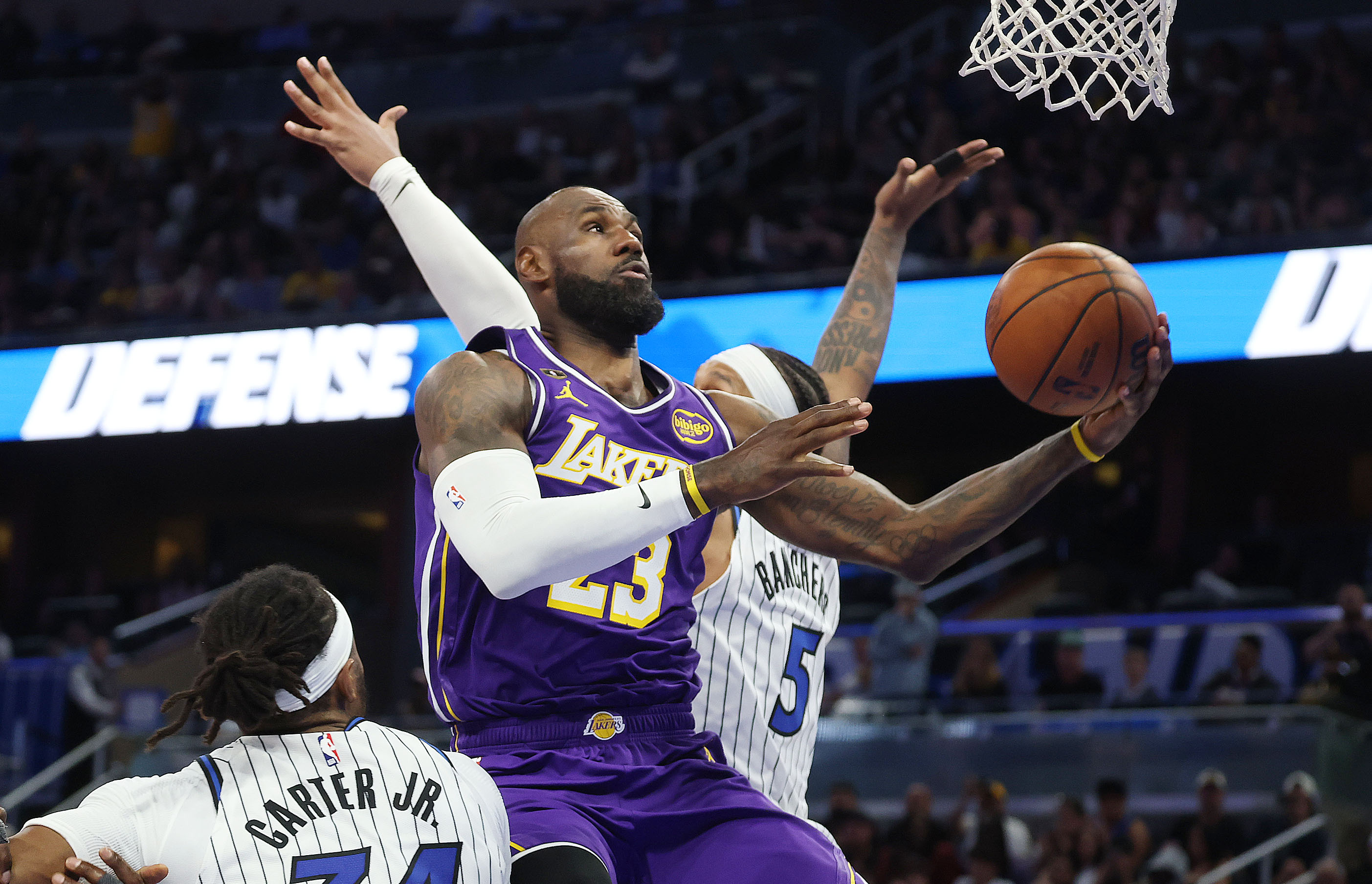 LA forward LeBron James (middle) scores over Orlando center Wendell...