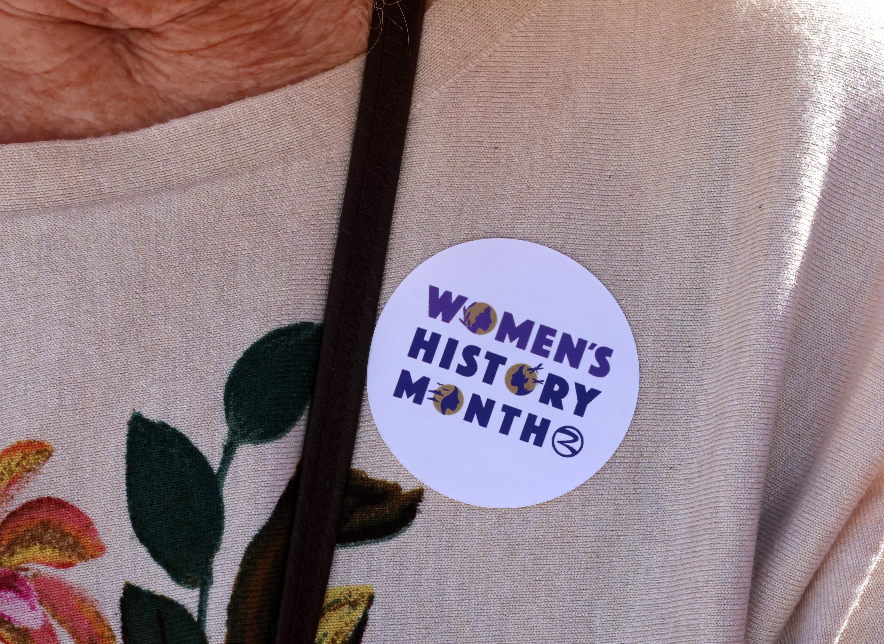 A woman wears a Women's History Month sticker during the...