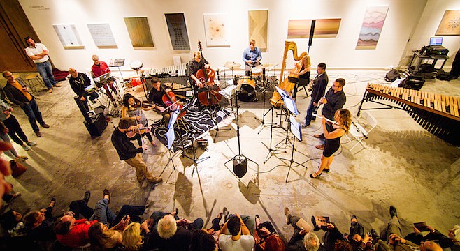 Photo taken from above of a classical musical ensemble performing in an art gallery