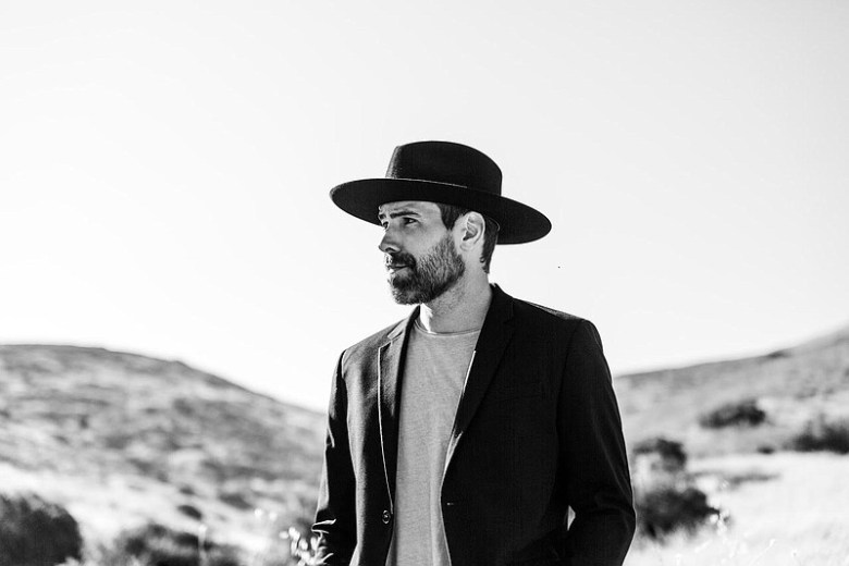 Black and white photo of a man in a black wide-brimmed hat outdoors