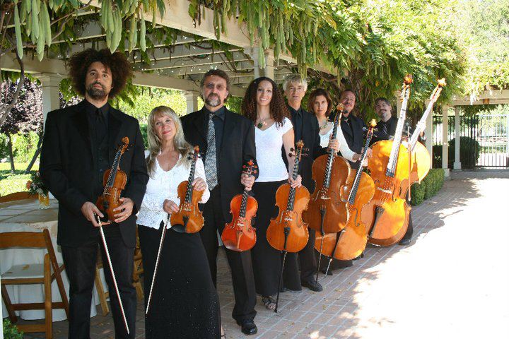 Photo of a classical music ensemble standing under a grape arbor