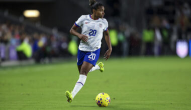 A player in a blue and white uniform dribbles a soccer ball on the field