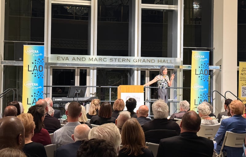 Dr. Kuo lectures from a stage to a full audience.