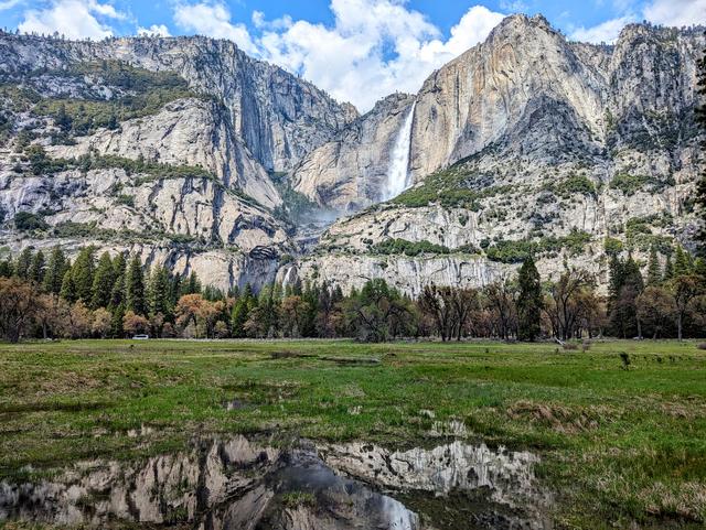Yosemite Falls, and its reflection in a puddle of water in the meadow below, is seen on April 23, 2024, at Yosemite National Park. 