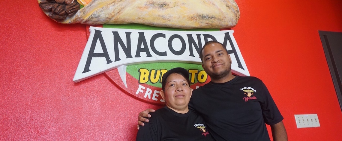 mother and son posing in front of a sign