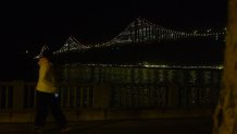 A woman walks down the Embarcadero past the Bay Lights.