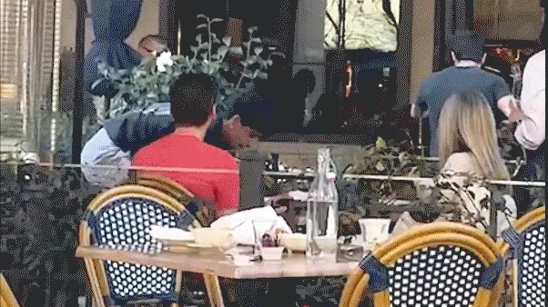 Two men appear to shove and lunge toward each other near an outdoor dining area