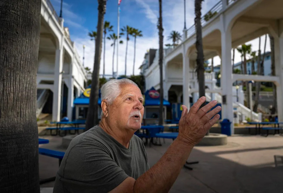 A man with gray hair gestures as he speaks.