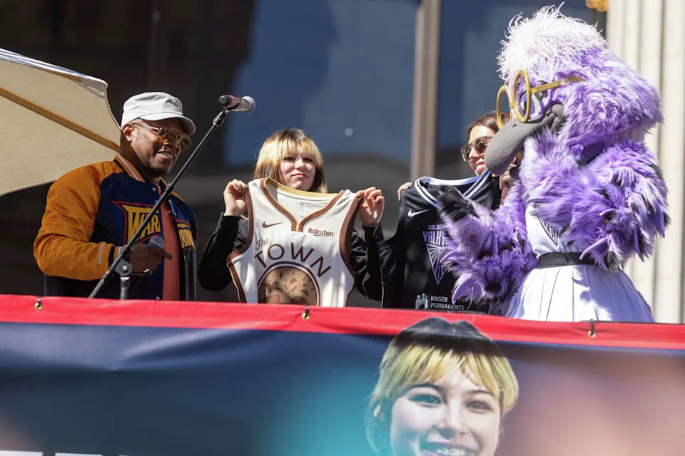 Olympic gold medalist Alysa Liu holds a "The Town" Golden State Warriors jersey awarded to her during the Alysa Liu Celebration Rally at Frank Ogawa Plaza in front of Oakland City Hall in Oakland, Calif., on March 12, 2026. (Douglas Zimmerman/SFGATE)