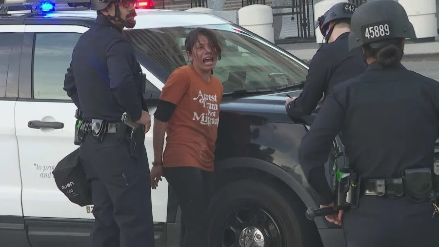 Officers detain protesters as mounted police and tactical units respond to clashes during the “No Kings” protest in downtown Los Angeles.