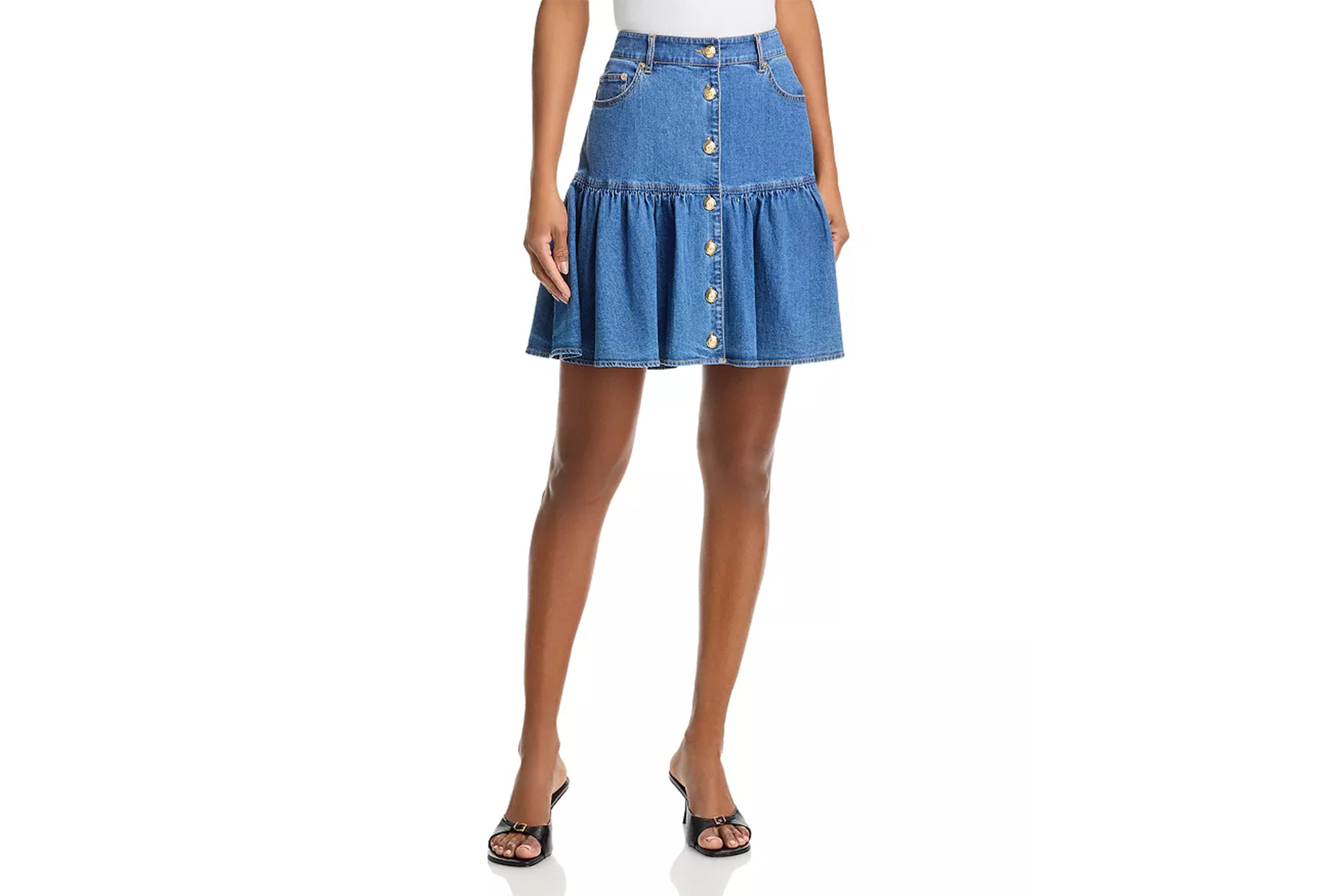 A model wearing a Cinq à Sept denim mini skirt with gold button-front details.