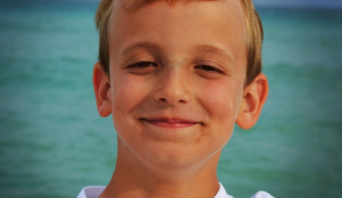 Connor Metz's legacy includes life-saving training of 1500 nursing students. Connor is pictured here smiling in front of the ocean in a white tee-shirt. He lost his life at 13 due to undiagnosed Loeys-Dietz syndrome and aortic dissection.
