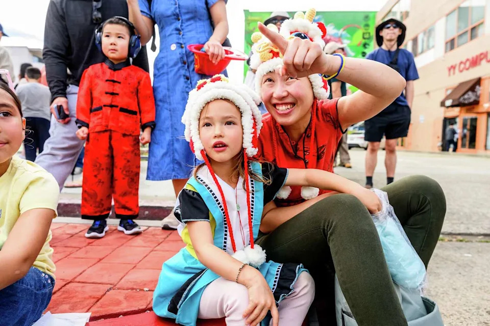 Kestrel Kula, center, and Sharon Liu marvel at Saturday's Oakland Chinatown Lunar New Year Parade. (Noah Berger/For the S.F. Chronicle)