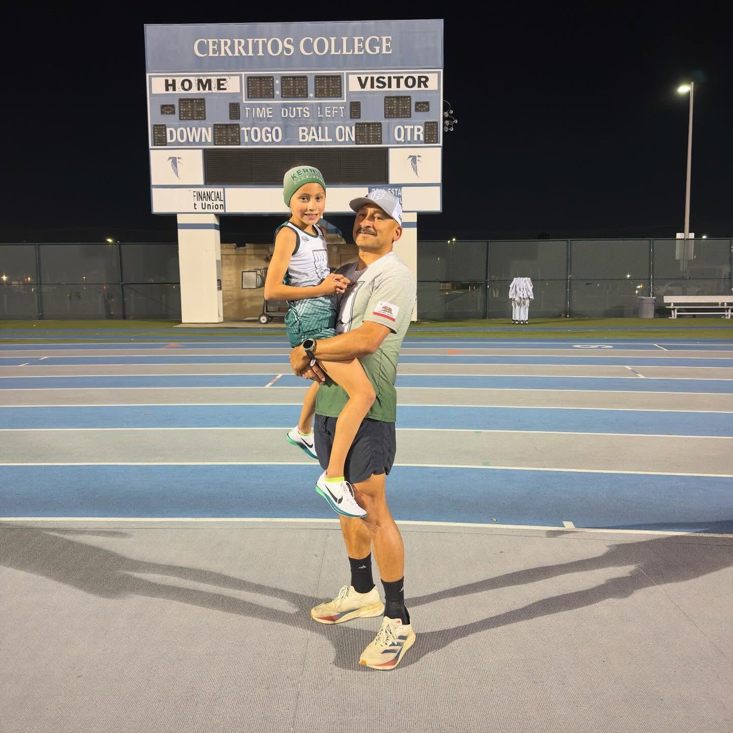 Emelie Chavez, the fastest 7-year-old in the world, being held by her father at Cerritos College stadium.