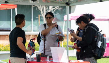 multiple people talking to a representative at an outdoor vendor booth