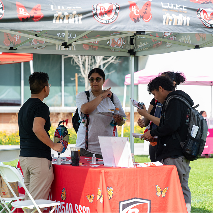 multiple people talking to a representative at an outdoor vendor booth