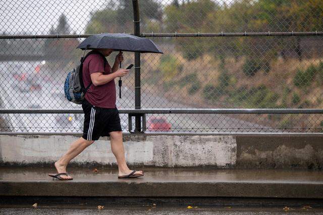 A pedestrian walks in the rain on 48th Street over Highway 50 in Sacramento in 2022. California drivers strike and kill about 1,000 people walking each year, and many of those crashes are considered preventable with infrastructure changes.