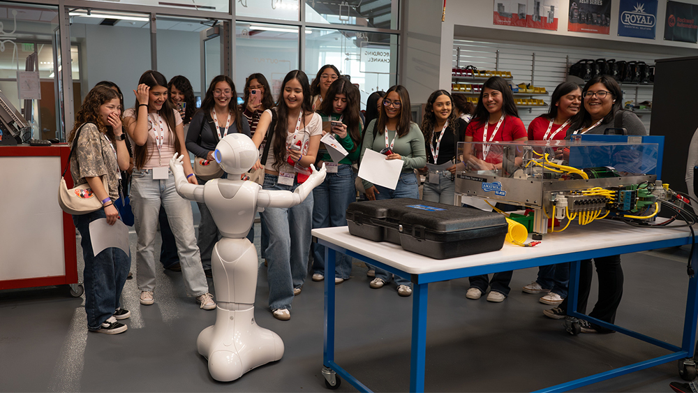 several high school girls watching a robot in a classroom