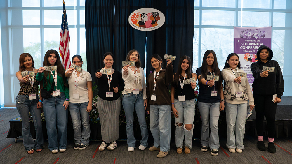 young women standing next to each other holding money