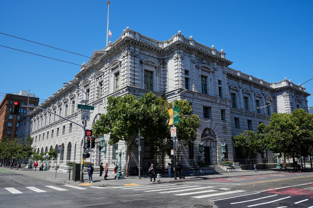 The US Ninth Court of Appeals building, a large, ornate building made of light-colored stone, seen from a street corner in San Francisco.