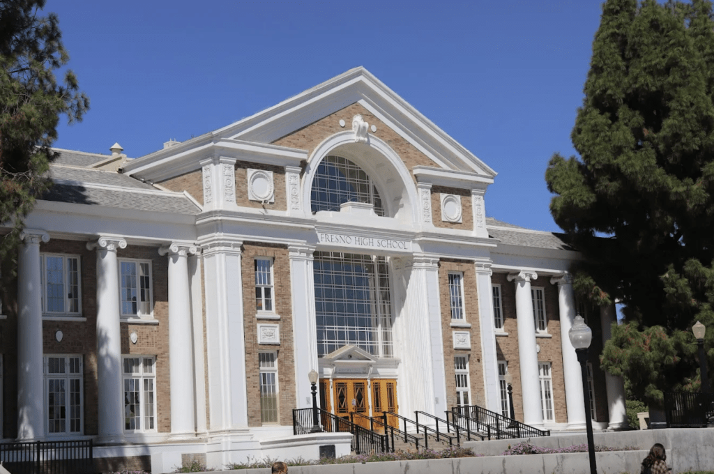 A large, classical-style brick building with the words "Fresno High School" above the main entrance.