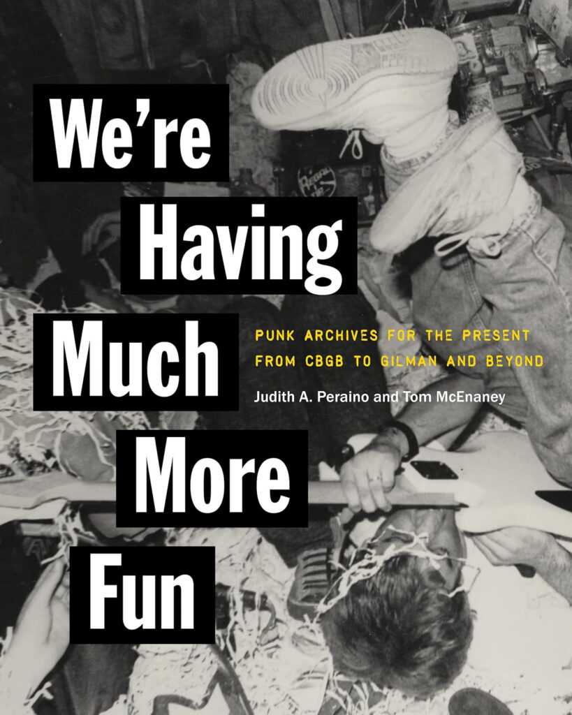 Black-and-white book cover titled "We’re Having Much More Fun" in bold, black-boxed text. The background photo shows a chaotic punk scene with a person holding a guitar on a streamer-covered floor while another person’s legs and sneakers are in the air.
