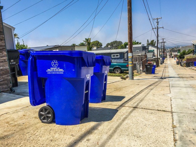 Recycling and trash bins line an alley in Ocean Beach.
