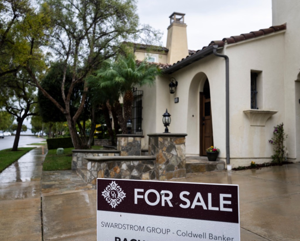 A "FOR SALE" sign sits in front of a house in Irvine, California.