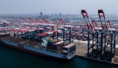 A cargo ship is moored in the Port of Long Beach while cranes retrieve cargo containers from the ship