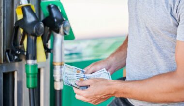 Image of a man holding $100 bills getting ready to buy gasoline at the pup