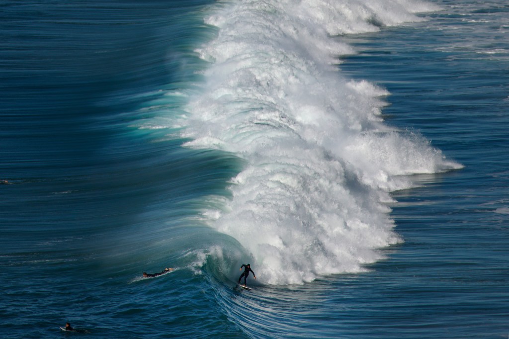 A surfer riding a large wave at Black's Beach in La Jolla.