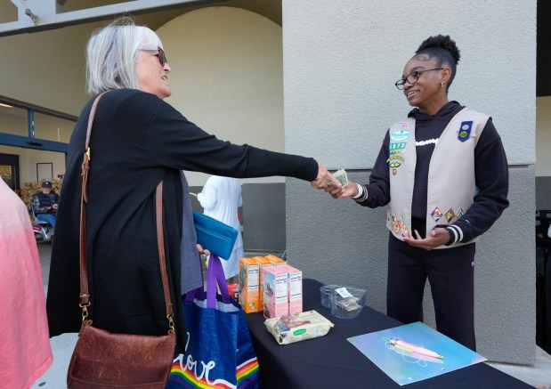 From her booth table set up in front of a local grocery store on Third Avenue in Chula Vista, Lyric Nolan, 13, sold a box of Girl Scout cookies to Kelly Engelman of Chula Vista. To date Lyric has sold more than 500 boxes of Girl Scout cookies. (Nelvin C. Cepeda / The San Diego Union-Tribune)