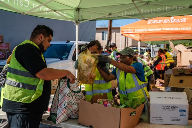 Pastor David Villalobos and Graciela Castellanos, helps a woman fill up her bag at a food distribution with food from Feeding San Diego at Iglesia Casa de Alabanza in City Heights  on March 26, 2026. (Ariana Drehsler / For The San Diego Union-Tribune)