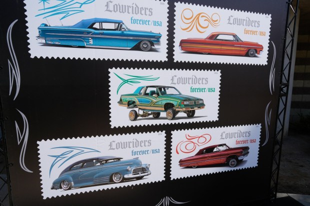 The five new U.S. postal stamps displayed on a large banner paying tribute to lowriders were unveiled during a ceremony at the Logan Heights Library in San Diego on Friday, March 13, 2026. (Nelvin C. Cepeda / The San Diego Union-Tribune)