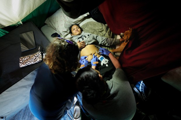 At an encampment along Int. 805, Lisa Silvestro (l), 52, a nurse practitioner, and Prizma Mercado (r) gave Dulce Delgado her 2nd pre-exposure prophylaxis (PREP) treatment. Silvestro and Mercado are health professionals with Healthcare in Action and offer medical care to those who have become homeless.  (Nelvin C. Cepeda / The San Diego Union-Tribune)