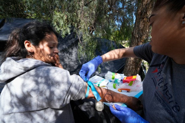 Prizma Mercado draws blood from one of her patients, Dulce Delgado, for an HIV test. Mercado is teamed up with Lisa Silvestro, a nurse practitioner with Healthcare in Action who offers medical care to those who are experiencing homelessness and living in encampments. (Nelvin C. Cepeda / The San Diego Union-Tribune)
