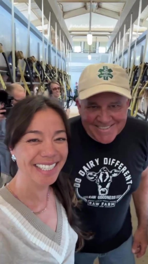 A woman and man smiling in what appears to be a dairy barn, with the man wearing a "Do Dairy Different" t-shirt.
