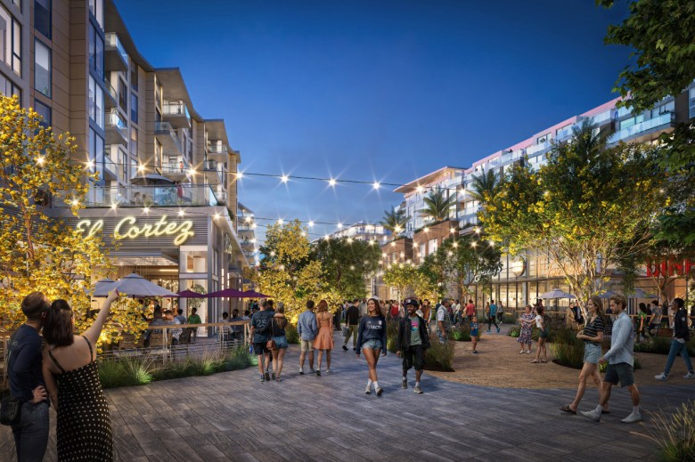 People walk through a plaza surrounded with buldings, lights and trees.