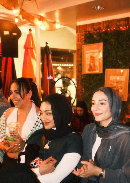 Three women smile on a backdrop of colorful art and decor.