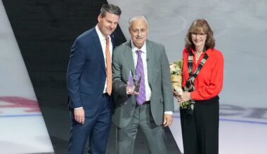 Dec 19, 2025; Anaheim, California, USA; Anaheim Ducks radio broadcaster Steve Carroll (center) poses with wife Rhonda Carroll (right) and Ducks president Aaron Teats to honor Carroll's career broadcast before the game against the Dallas Stars at the Honda Center. Mandatory Credit: Kirby Lee-Imagn Images