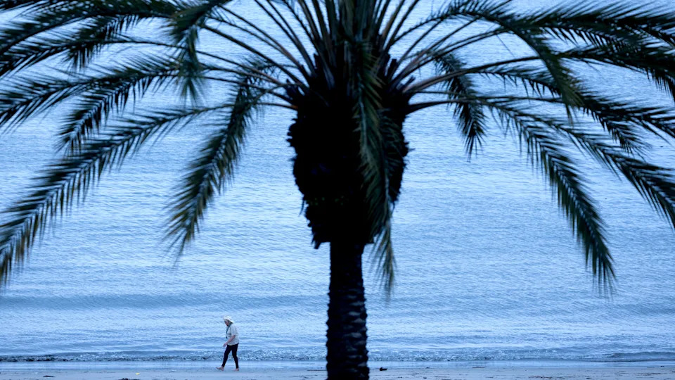 A person is seen walking along the shore of Long Beach in California.
