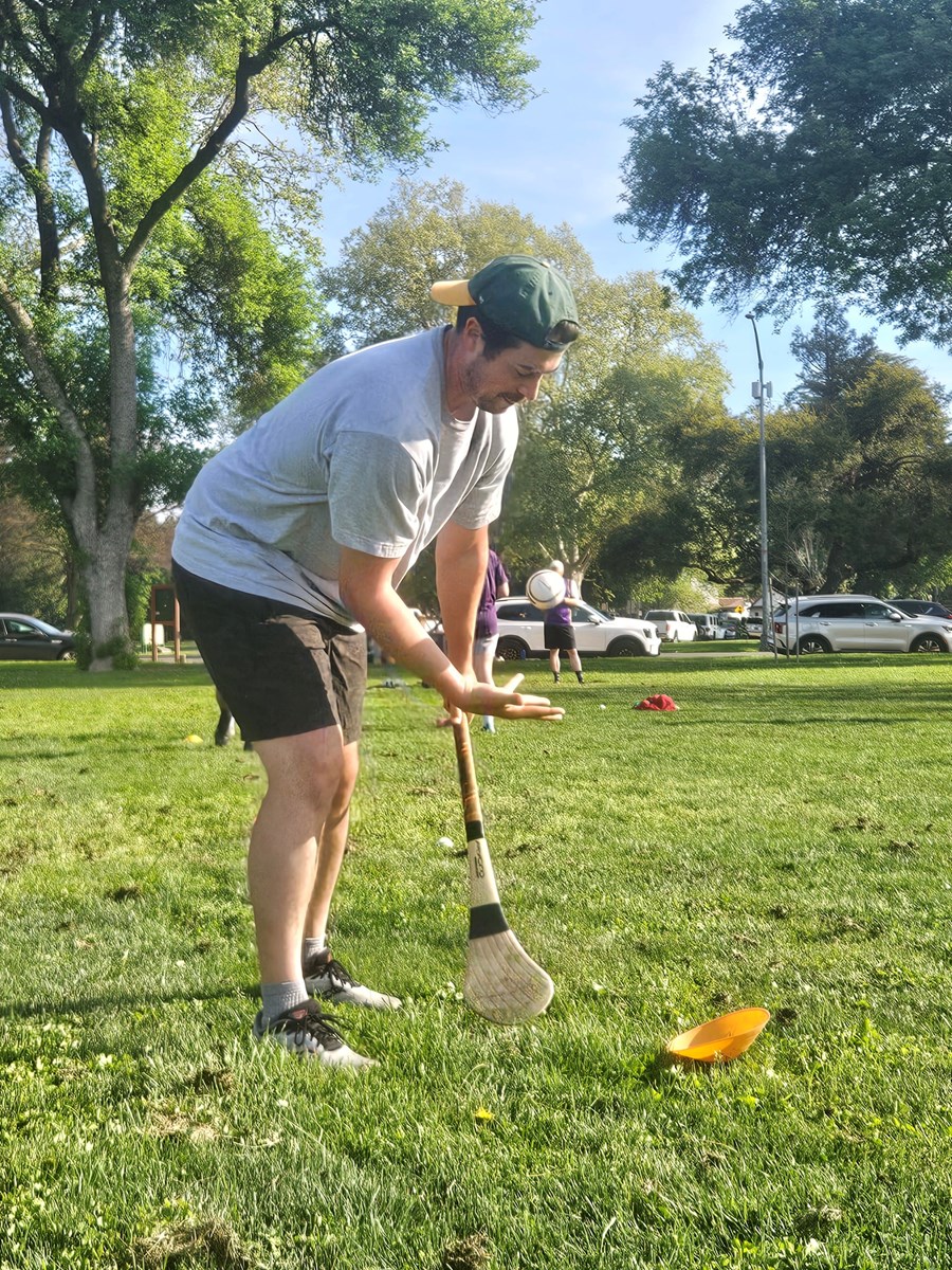 New hurling player Gareth Durham scoops up a sliotar with his hurley Saturday, March 21, 2026 in Sacramento.