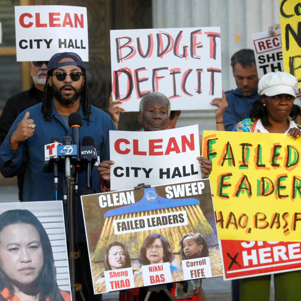 Seneca Scott and other protestors holding signs demanding to “Clean City Hall” due to “Budget Deficit” and “Failed Leaders.”